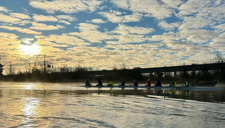 Image of a sunrise over a river with rowing teams in boats on the river