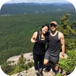 Two people standing on a cliff with trees